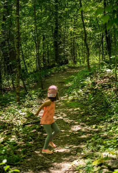 Malá holčička v lese se dívá na stezku s hrůzostrašným postojem — Stock fotografie