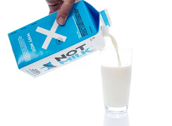 Cartón de NotMilk leche alternativa vertido en vaso de vidrio —  Fotos de Stock