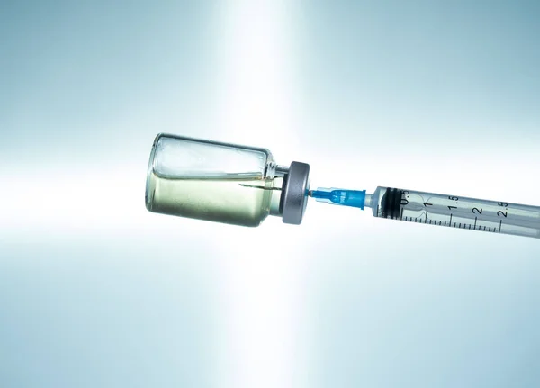 Hypodermic syringe needle inserted into a vaccine ampoule or bottle — Stock Photo, Image