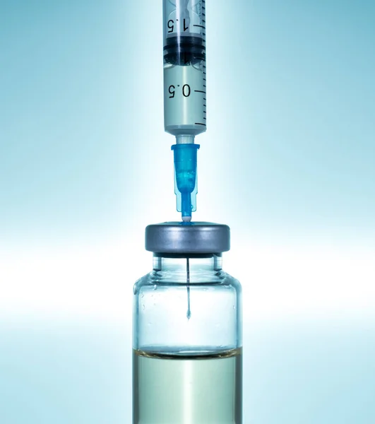 Hypodermic syringe needle inserted into a vaccine ampoule or bottle — Stock Photo, Image