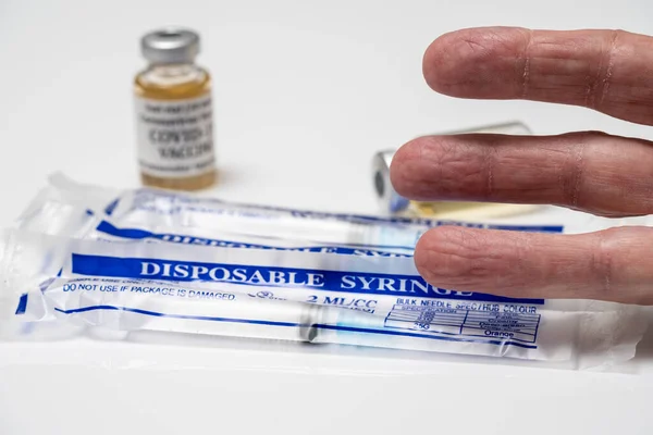 Concept for Covid-19 booster dose or shot using three fingers above wrapped disposable syringes — Stock Photo, Image