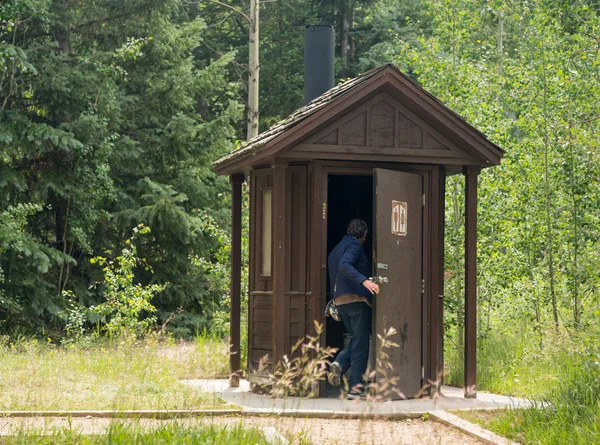 Woman entering restroom in forest — Stock Photo, Image