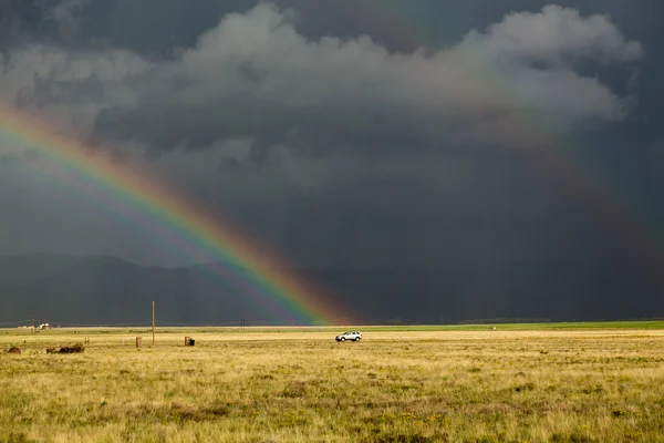 Sun shining on grassland under storym and rain — Stock Photo, Image