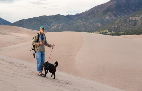 Man met hond op grote zandduinen np — Stockfoto