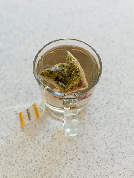Bolsita de té de manzanilla en taza de vidrio en la mesa —  Fotos de Stock