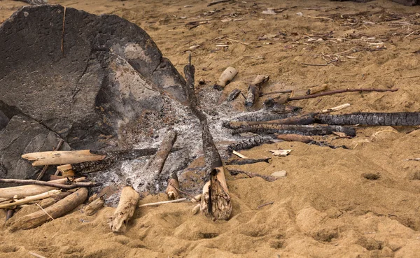 Remains of campfire on sandy beach — Stock Photo, Image