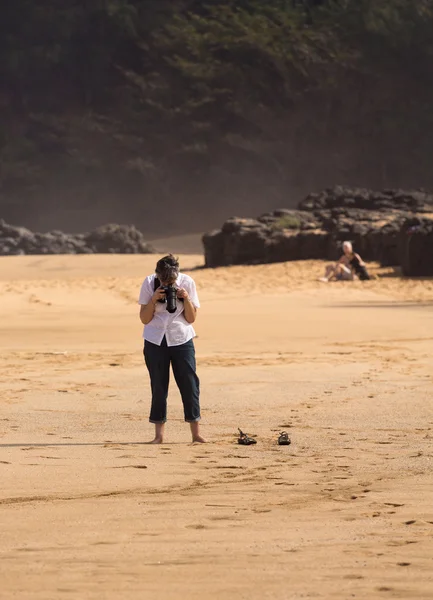 Mujer mayor toma fotos en la playa — Foto de Stock