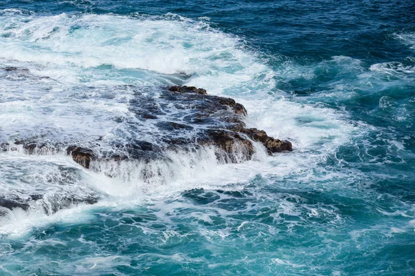 Razende zee stromen over lave stenen op kustlijn — Stockfoto