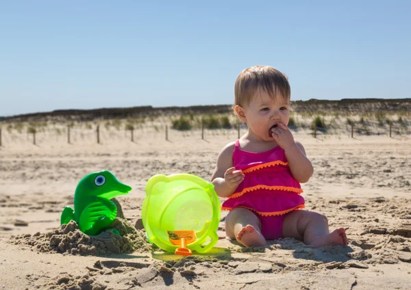 Dziecko dziewczynka degustacja piasku na plaży — Zdjęcie stockowe