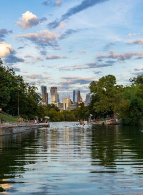 Gün batımında Austin Skyline ile Barton Springs yüzme havuzunda yüzücüler
