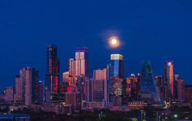 Austin Texas siluetinin hava aracı görüntüsü ofis binaları tarafından dolunayın yükseldiği görülüyor. Zilker Park ön planda..