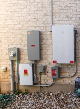 Leander, TX - 31 Ekim 2025: Tesla Powerwall pil mağazası ile birlikte evin yan tarafında güneş enerjisi kurulumu ve anahtar dişli çevirici