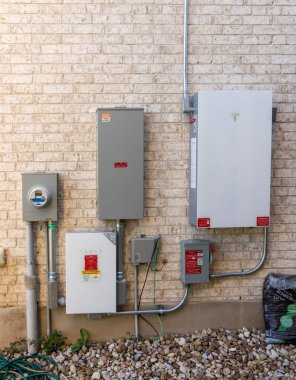 Leander, TX - 31 Ekim 2025: Tesla Powerwall pil mağazası ile birlikte evin yan tarafında güneş enerjisi kurulumu ve anahtar dişli çevirici