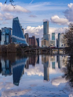 Austin silueti üzerinde bulutlar uçuşurken, binalar öğleden sonra Colorado nehrinin sakin sularını yansıtıyor..