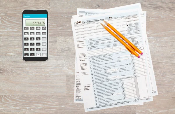 Calculator app on smartphone with 2015 IRS form 1040 — Stock Photo, Image