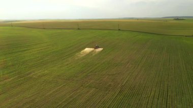 Gün batımında soya tarlası otlarını ilaçlayan bir tarım traktörünün hava görüntüleri. Ukrayna, Avrupa 'nın tarım bölgesi. Sinematik drone çekimi. UHD 4k video 'da çekildi. Güzel toprak.