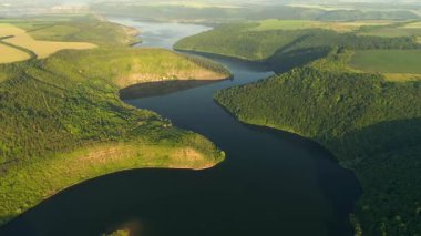 Yeşil tepelerden akan kıvrımlı nehrin panoramik manzarası kuş bakışı. UHD 4k video ile çekildi.