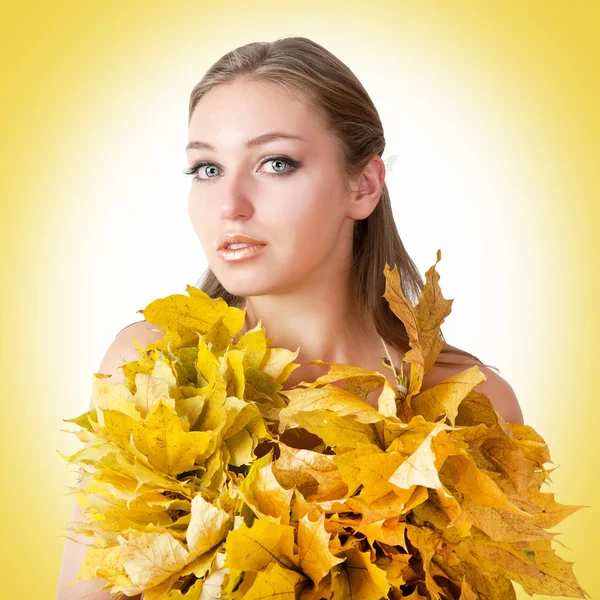 Beautiful woman with autumn leaves on yellow background. — Stock Photo, Image