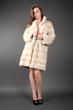 Genç esmer Bayan yün ceket gri arka plan üzerinde poz.