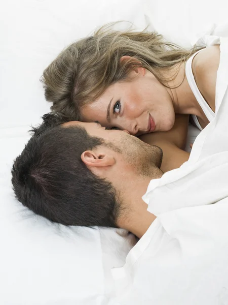 Attractive couple in love under white bed sheets — Stock Photo, Image