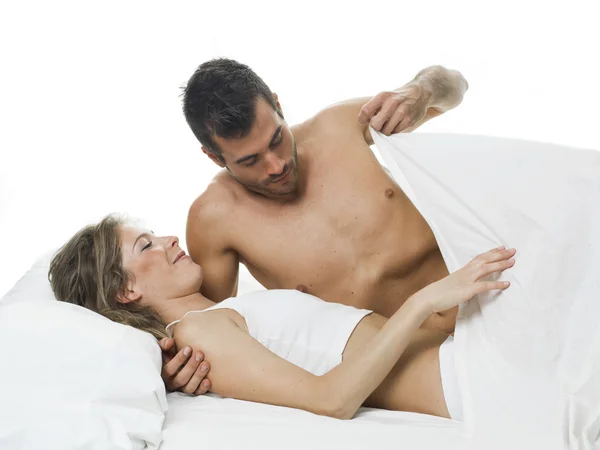 Divertida pareja prejugando en una cama blanca y sábanas — Foto de Stock