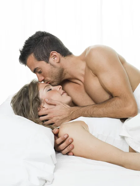 Człowiek całując swojego partnera słodko w białe łóżko — Zdjęcie stockowe