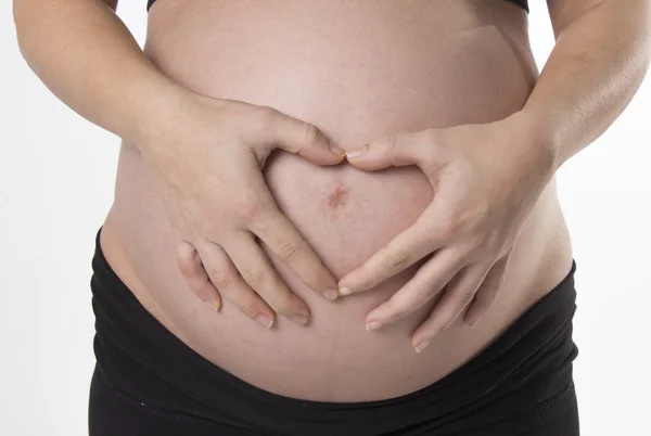 Беременная женщина держит руки на красивом животе — стоковое фото