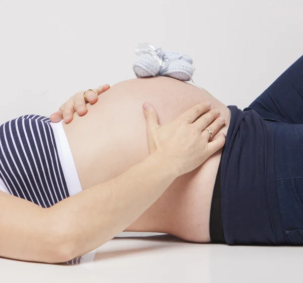 怀孕的女人抱着她双手放在腹部健美 — 图库照片