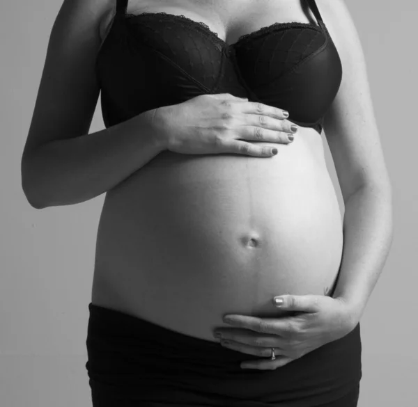 Mulher grávida segurando as mãos na bela barriga — Fotografia de Stock