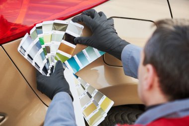 colourist man selecting color of car with paint matching samples clipart