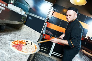 Şef baker aşçı pizza kıpırdamak içinde koyarak