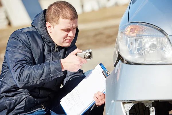 Insurance agent photographing car damage for claim form — Stock Photo, Image
