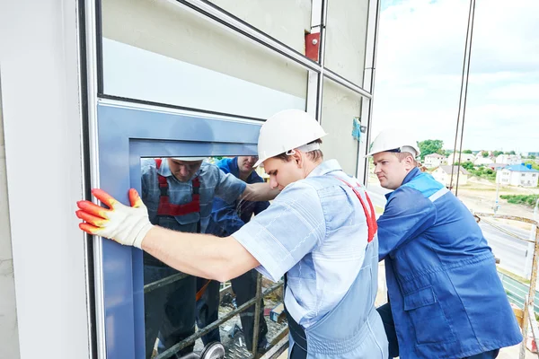 Constructores trabajador instalar ventanas de vidrio en la fachada — Foto de Stock