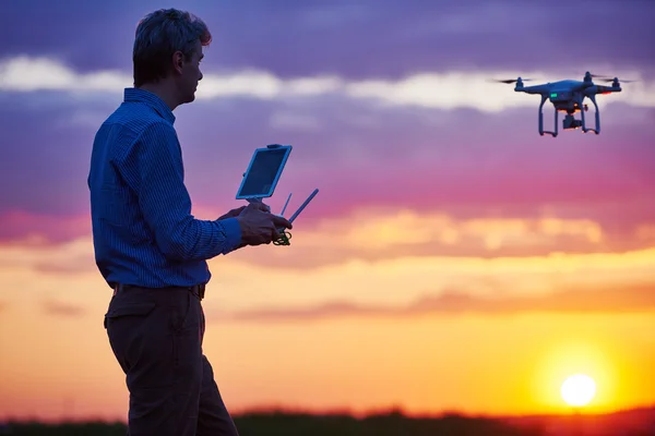 Człowiek pracy z latający dron o zachodzie słońca — Zdjęcie stockowe