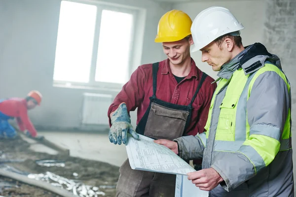 Foreman builder and construction worker with blueprint in indoor apartment — Stock Photo, Image