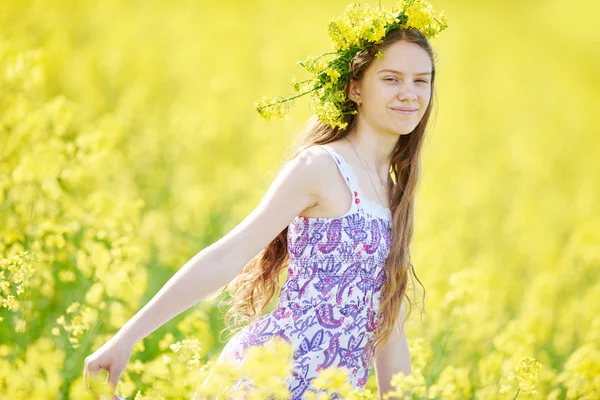 Menina com guirlanda flor no prado de sementes de colza amarelo — Fotografia de Stock