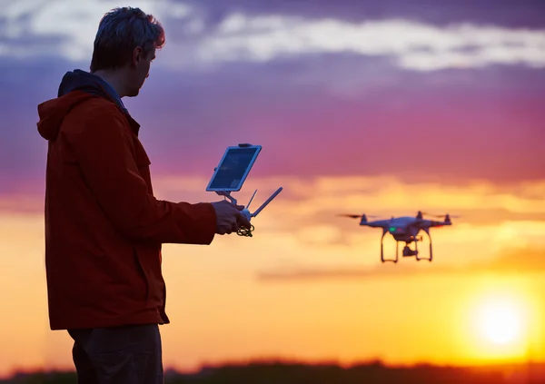 Człowiek pracy z latający dron o zachodzie słońca — Zdjęcie stockowe