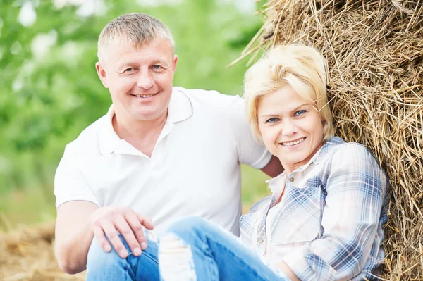Lachende volwassen paar in de buurt van hooiberg op platteland — Stockfoto