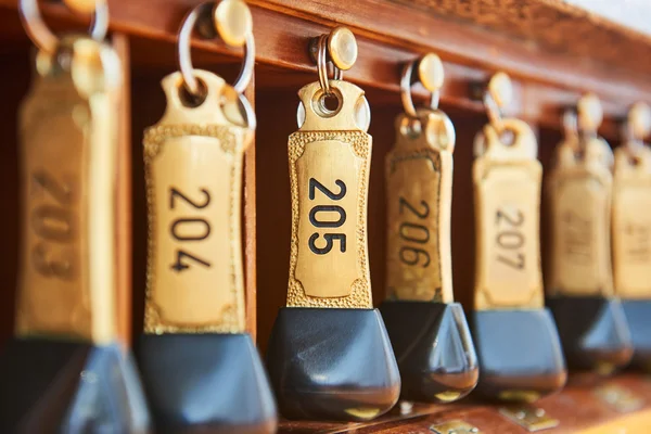 Ключі від готелю з номерами номерів, що висять на рецепції — стокове фото