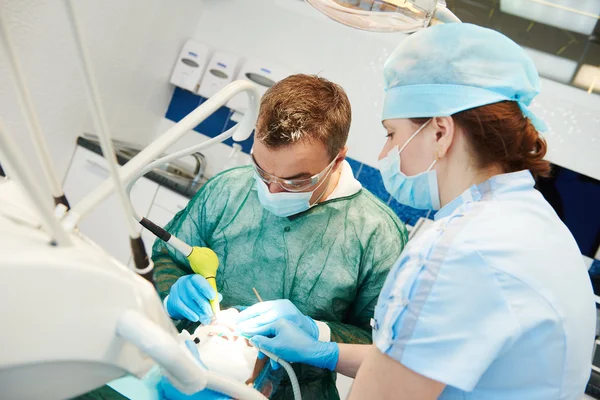 Médico dentista e assistente que trabalha com microscópio — Fotografia de Stock