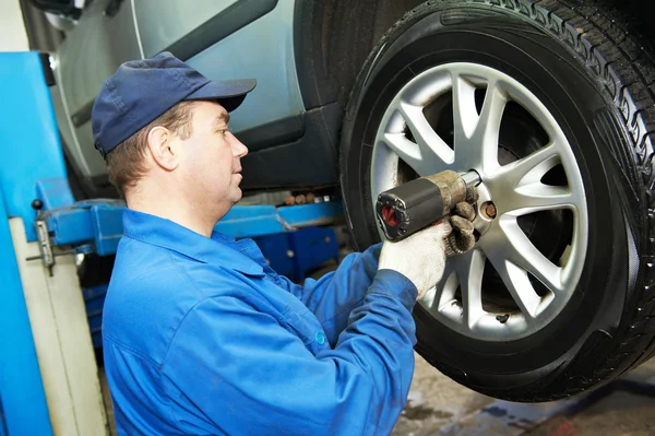 Auto mechanic screwing car wheel by wrench Stock Photo