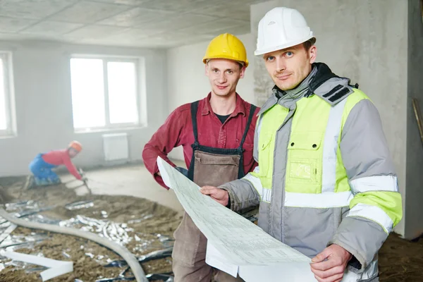 Foreman builder and construction worker with blueprint in indoor apartment — Stock Photo, Image