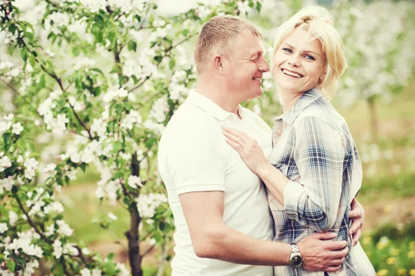 Lächelndes erwachsenes Paar im blühenden Apfelgarten — Stockfoto