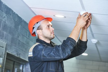 Tavana duman dedektörü yerleştiren işçiler