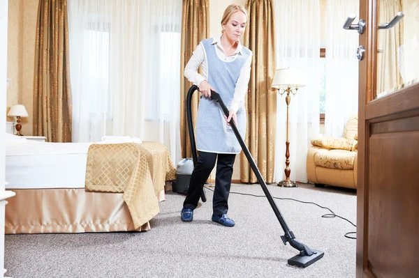 Hotel service. female housekeeping worker with vacuum cleaner