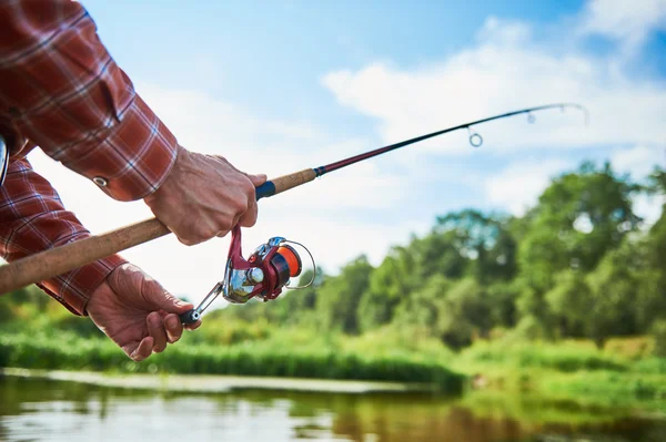 Fisherman holding spinning rod with reel while fishing — Stock Photo, Image