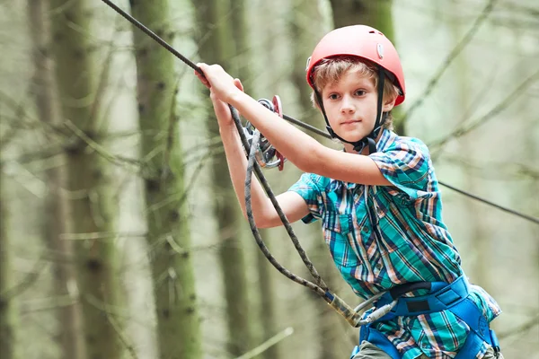 Niño en la actividad de escalada en el parque del bosque de alambre alto — Foto de Stock