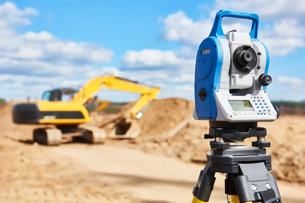 Equipamentos de topografia theodolie no local de construção com escavadeira — Fotografia de Stock