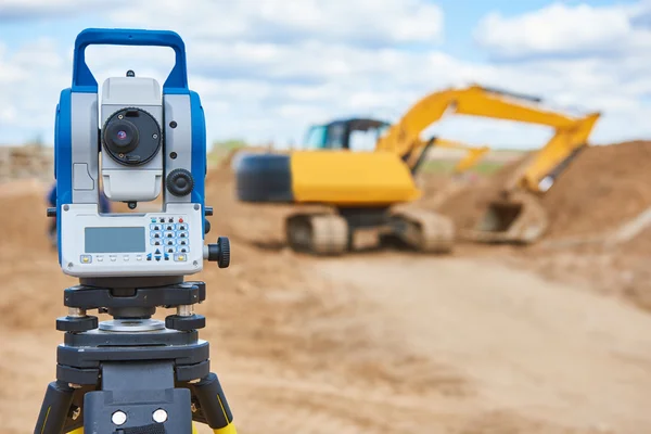 Equipamentos de topografia theodolie no local de construção com escavadeira — Fotografia de Stock