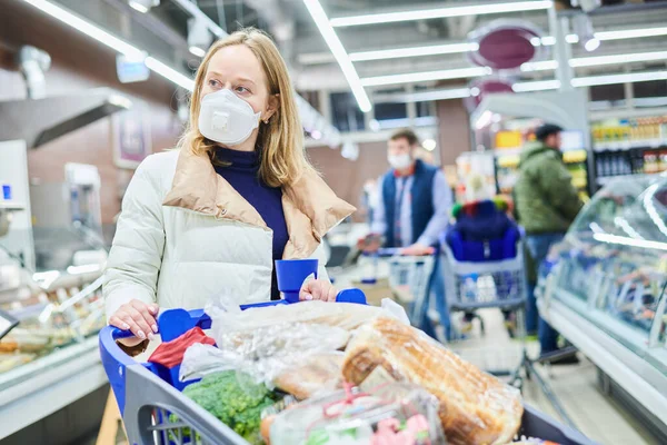 Mujer con máscara y guantes protectores comprando comida en tienda en coronavirus epidemia — Foto de Stock